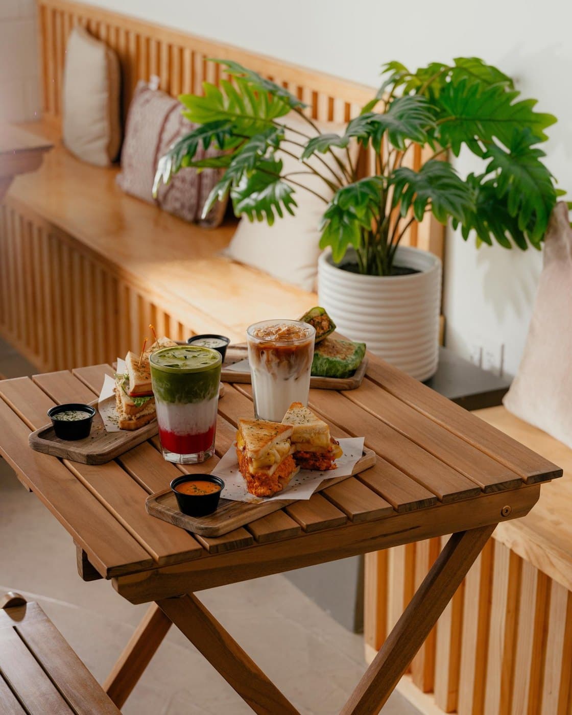 Mesa de Sumaq con sándwiches, un matcha en capas y un latte frío